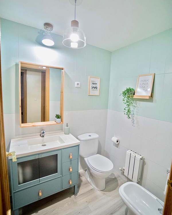 Un cuarto de baño con los azulejos pintados en dos colores verde menta y blanco