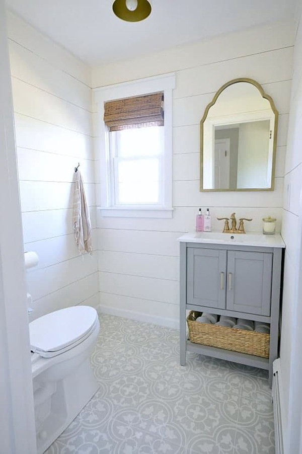 Un baño pequeño con las paredes revestidas de madera pintada de blanco