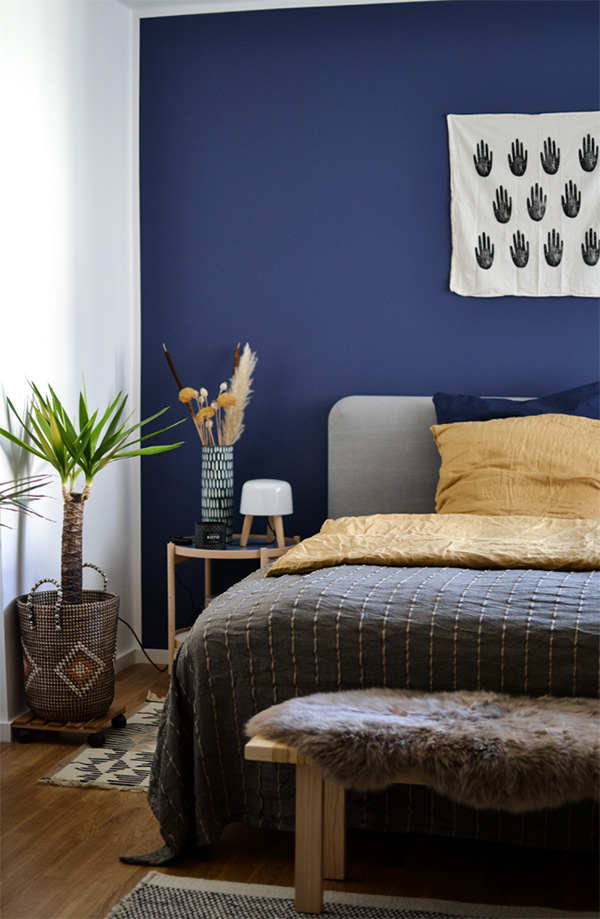 Un dormitorio que combina azul marino en paredes y amarillo en decoración