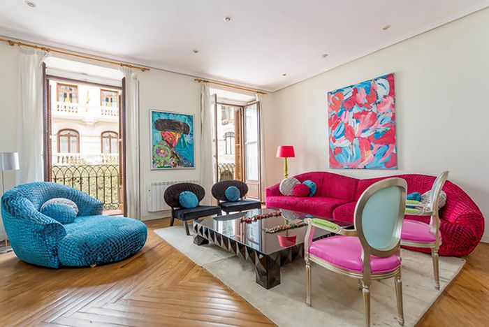 Un salón con paredes en blanco roto combinado con muebles rosas y azules