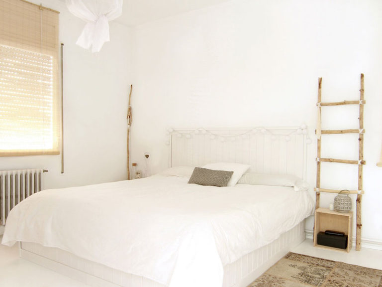 Un dormitorio matrimonial pintado de blanco