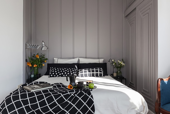 Un dormitorio con las paredes forradas de madera pintada de gris