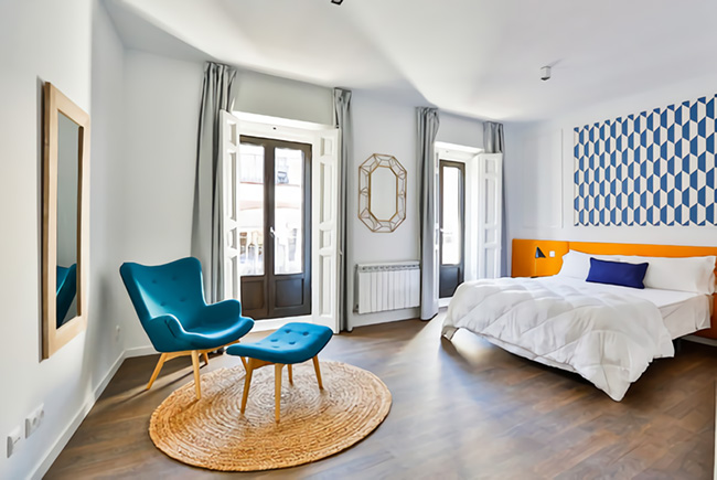 Un dormitorio en blanco con tonos azules, turquesa y naranjas