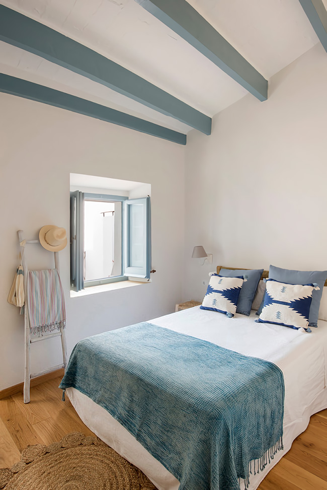 Un dormitorio en tonos blancos y azules con detalles rústicos