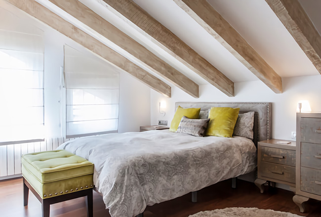 Un elegante y moderno dormitorio con vigas de madera en el techo