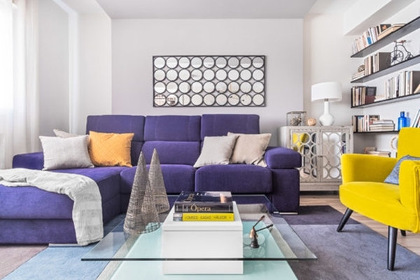 Sebuah bilik kecil dengan sofa ungu dan kerusi berlengan kuning