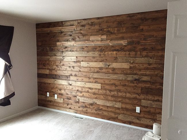 Un dormitorio de matrimonio con una pared revestida de madera
