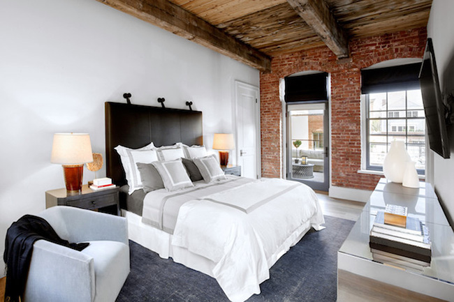 Un dormitorio blanco con paredes de ladrillos vistas