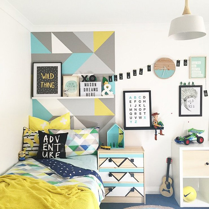 Una habitación infantil con una pared pintada con figuras geométricas