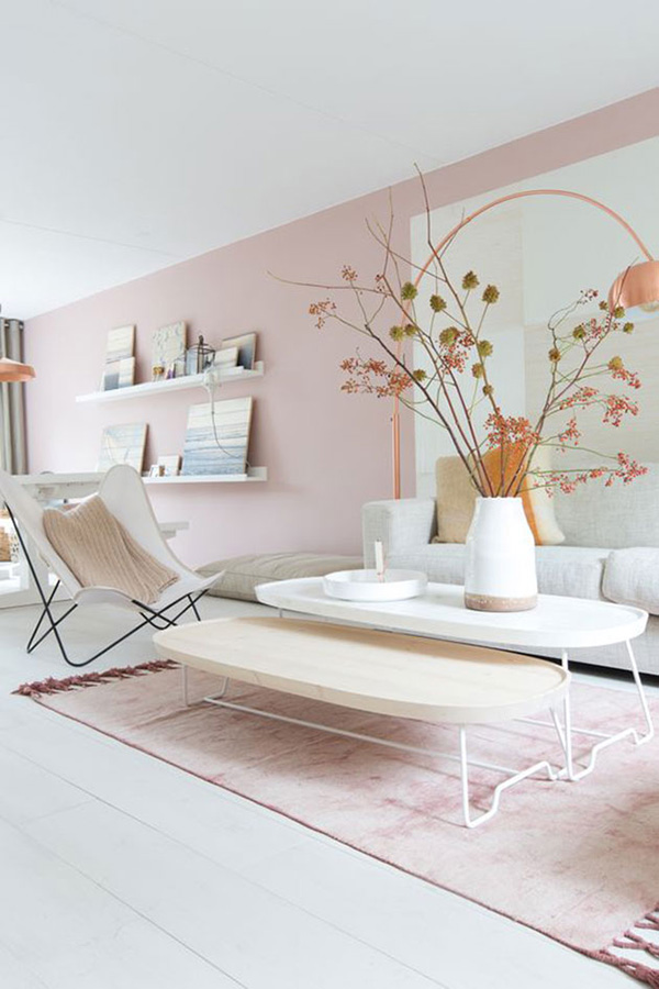 Un salón pintado de rosa con muebles blancos