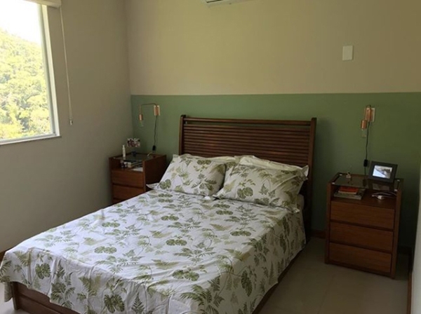 Un dormitorio pintado de verde y blanco, con un zócalo en la parte del cabecero